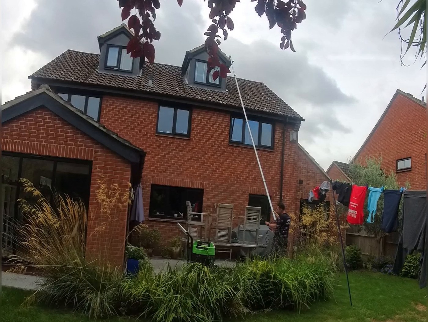 Rear elevation of the Fanshawe Road house in Thame with the gutter vacuum pole raised to the dormer-level guttering and the vacuum unit standing on the patio