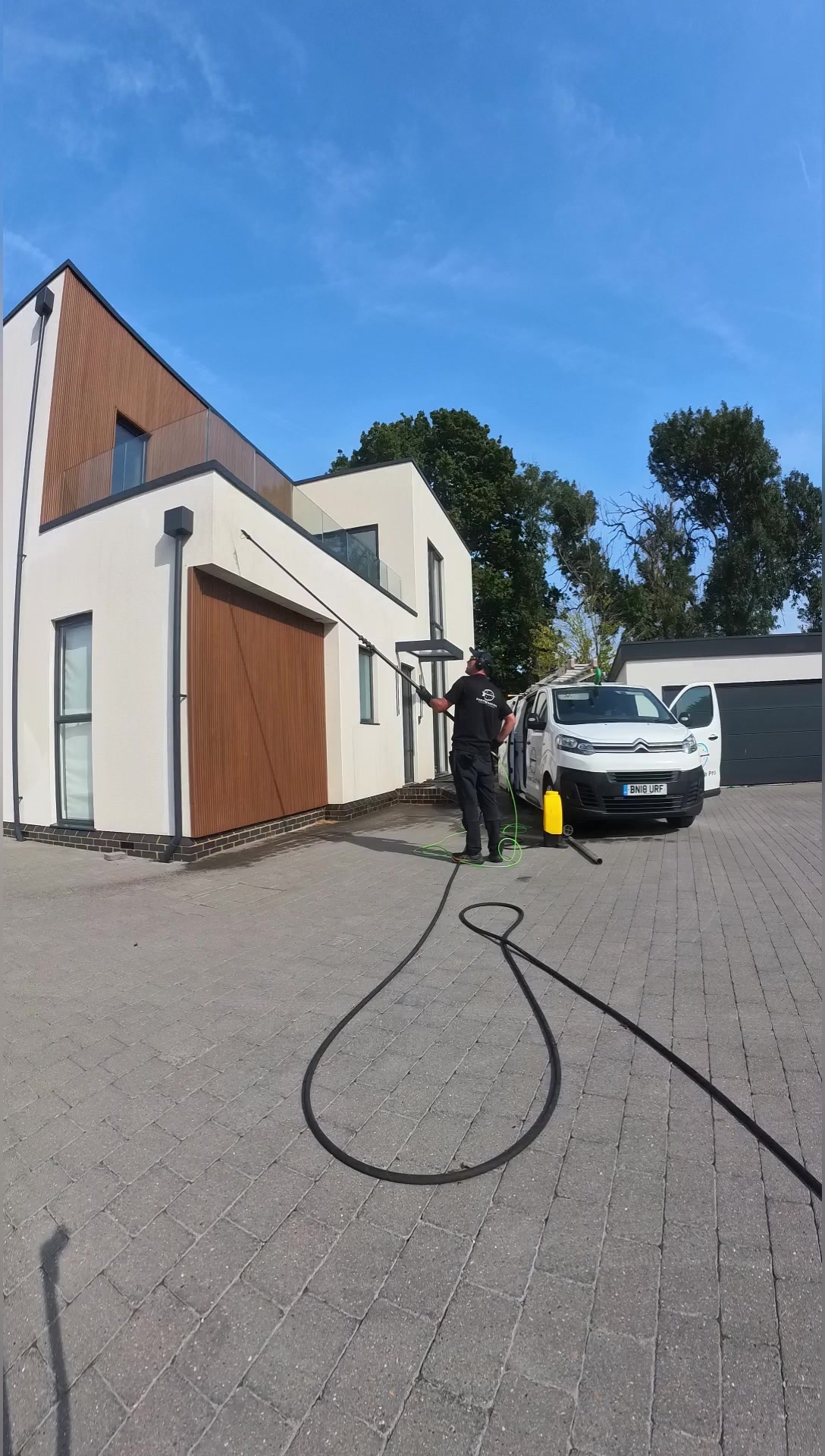 Andrew softwashing the K-Rend on a modern home in Great Kingshill with an extended pole, Power Wash Pro van on the drive