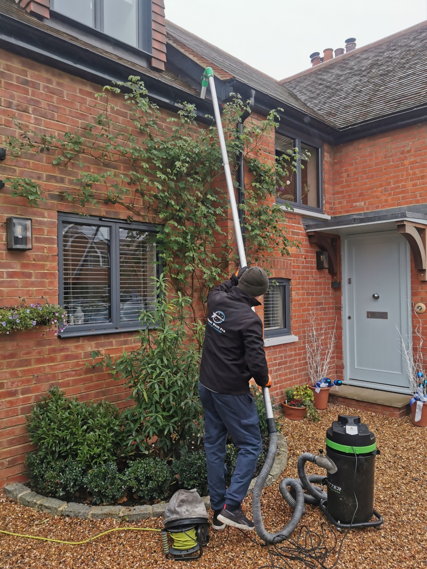 Andrew clearing gutters from the ground with a high-reach vacuum system