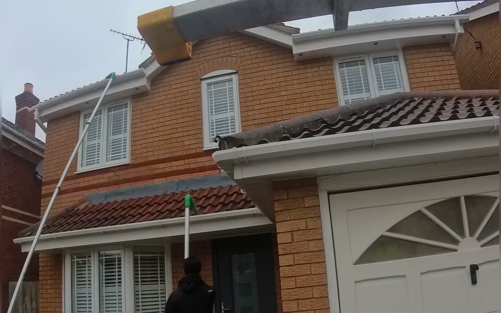 Andrew clearing the gutters of a modern detached house in Long Crendon using a high-reach gutter vacuum pole
